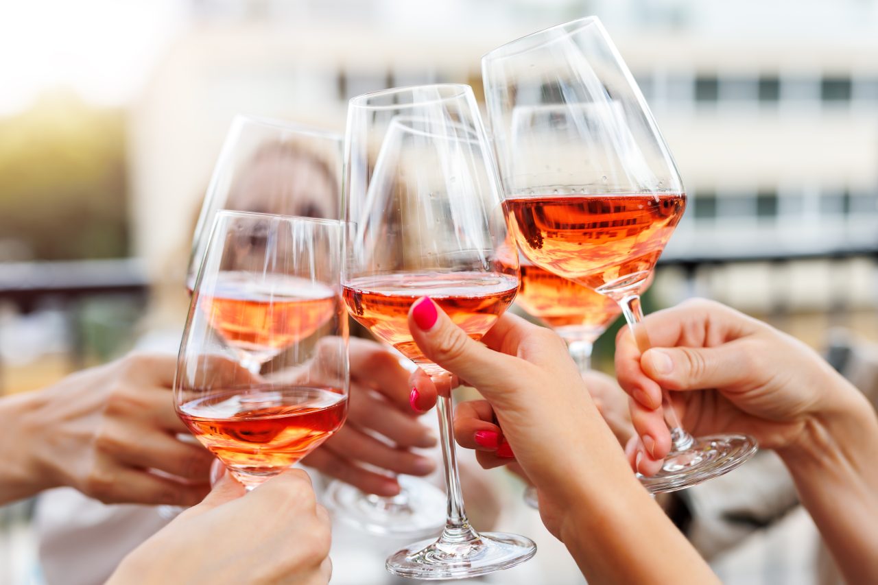 Close-up many female woman hands hold clinking rose wine glass celebrate toast party terrace warm sunset sun background. Girl friend enjoy drink champagne cocktail bachelorette event outdoor cafe bar.